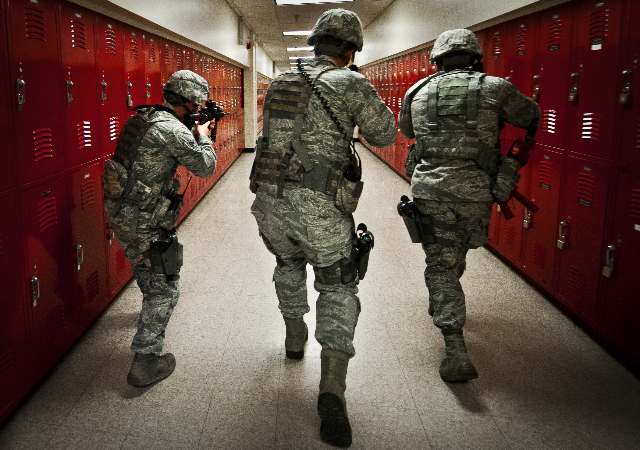 Soldiers walking in school with guns drawn.
