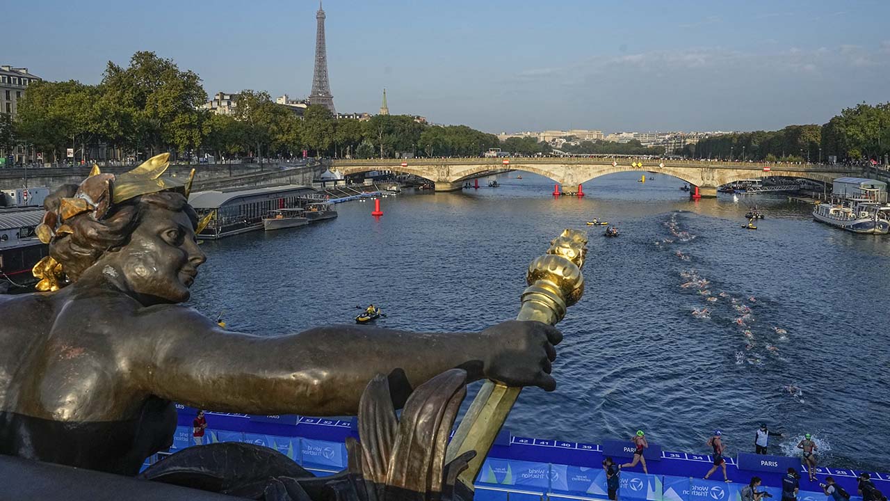 Athletes dive and swim in the Seine River from the Alexander III bridge on the first leg of the women's triathlon test event for the Olympics Games in Paris, Aug. 17, 2023. Water in the Seine River had unsafe elevated levels of E. coli less than two months before swimming competitions are scheduled to take place in it during the Paris Olympics, according to test results published Friday, June 14, 2024. (AP Photo/Michel Euler, File)
