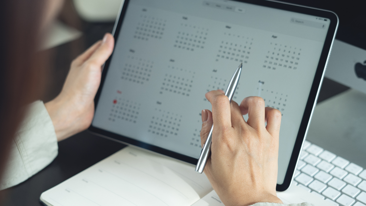 Business woman using digital tablet with monthly calendar for event planning