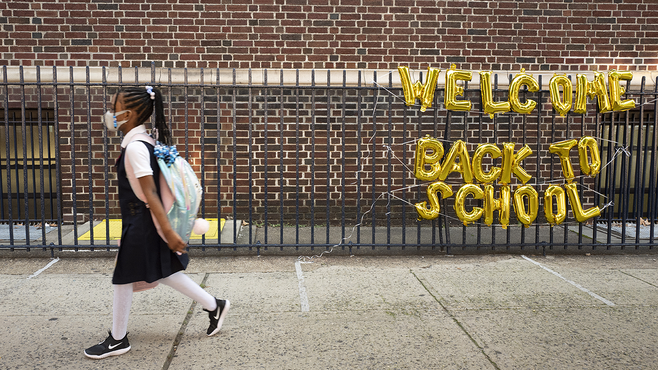 A girl passes a &quot;Welcome Back to School&quot; sign as she arrives for the first day of class at Brooklyn's PS 245 elementary school, Monday, Sept. 13, 2021, in New York (AP Photo/Mark Lennihan)