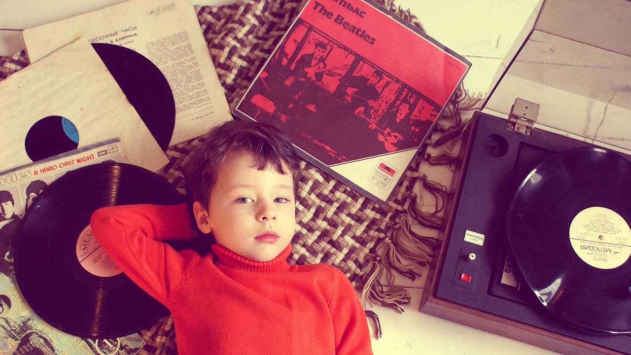 child lying on the floor listening to a record player