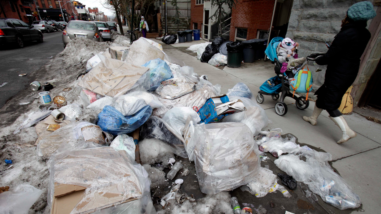 Pedestrians walk past a pile of garbage and snow mixed together in the Brooklyn borough of New York, Tuesday, Feb. 8, 2011. The mountains of snow may finally be melting away from New York City streets after more than a month of waist-high drifts but now there are new problems: pot holes, garbage piles five feet tall and black mounds of filthy, oozing refuse that no one wants to deal with. (AP Photo/Seth Wenig)
